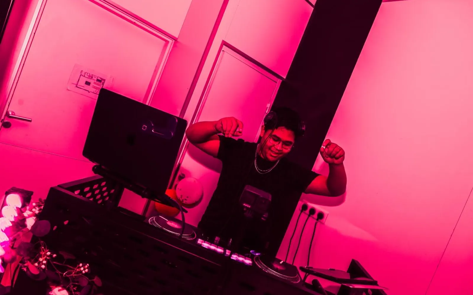 DJ Mélo aux platines sous un éclairage rose pendant une réception