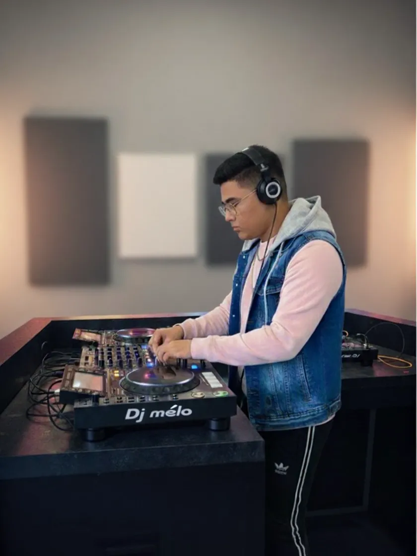 DJ Mélo au casque derrière son contrôleur, penché sur ses platines