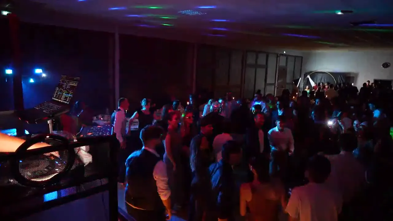 DJ Mélo aux platines, de dos, face à une piste de danse comble